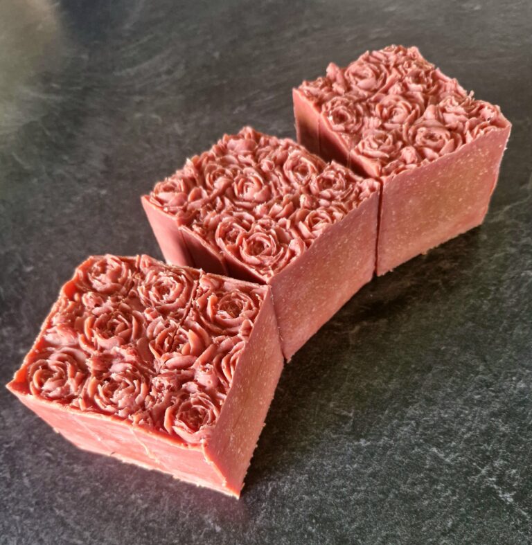 Three Fatglow tallow soap blocks in deep pinks showing off rose mold tops