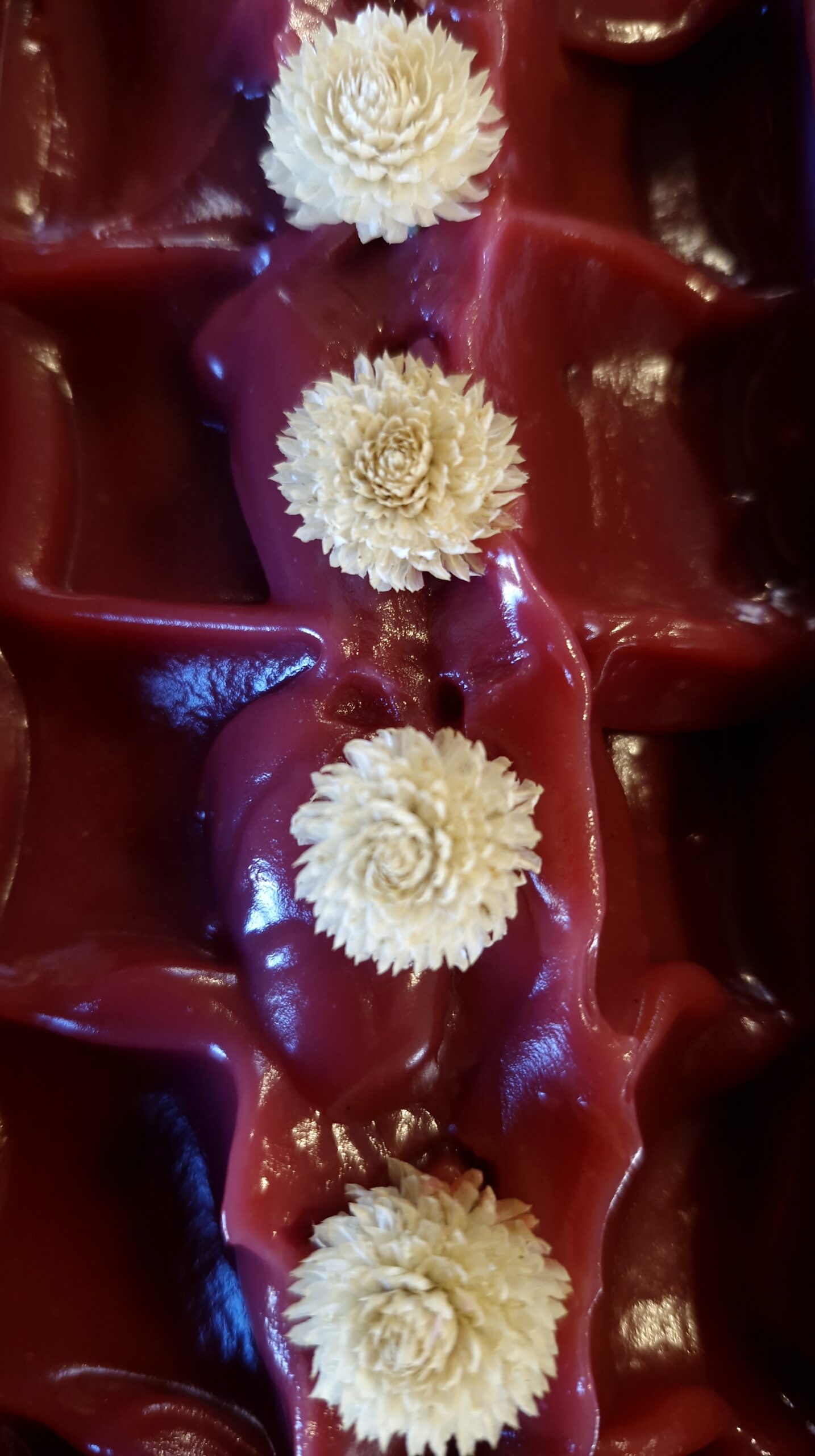 Deep red swirled tallow soap topped with dried cream flowers, handmade by Fatglow